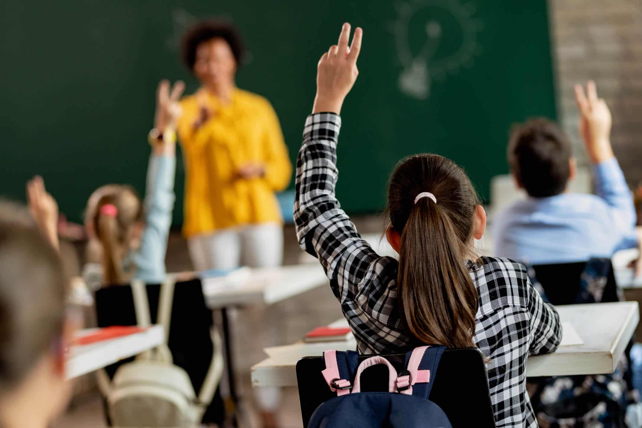 Students raising hands to answer questions in an energy-efficient classroom.