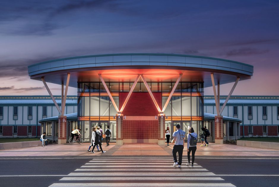 Warsaw Community High School exterior of new, remodeled entrance lit up at night with students walking in