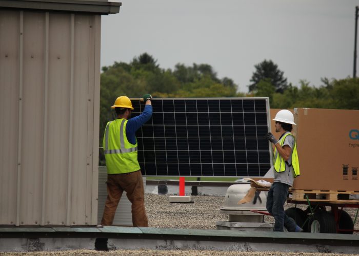 Two solar installers holding a solar panel