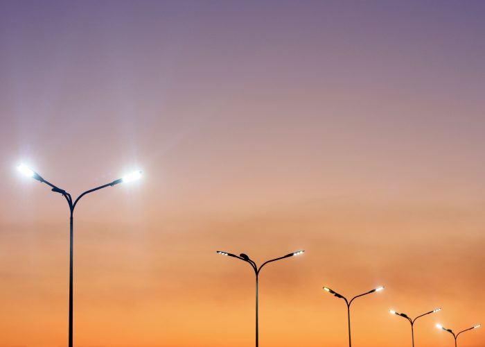 Smart street lights illuminated against a sunset sky