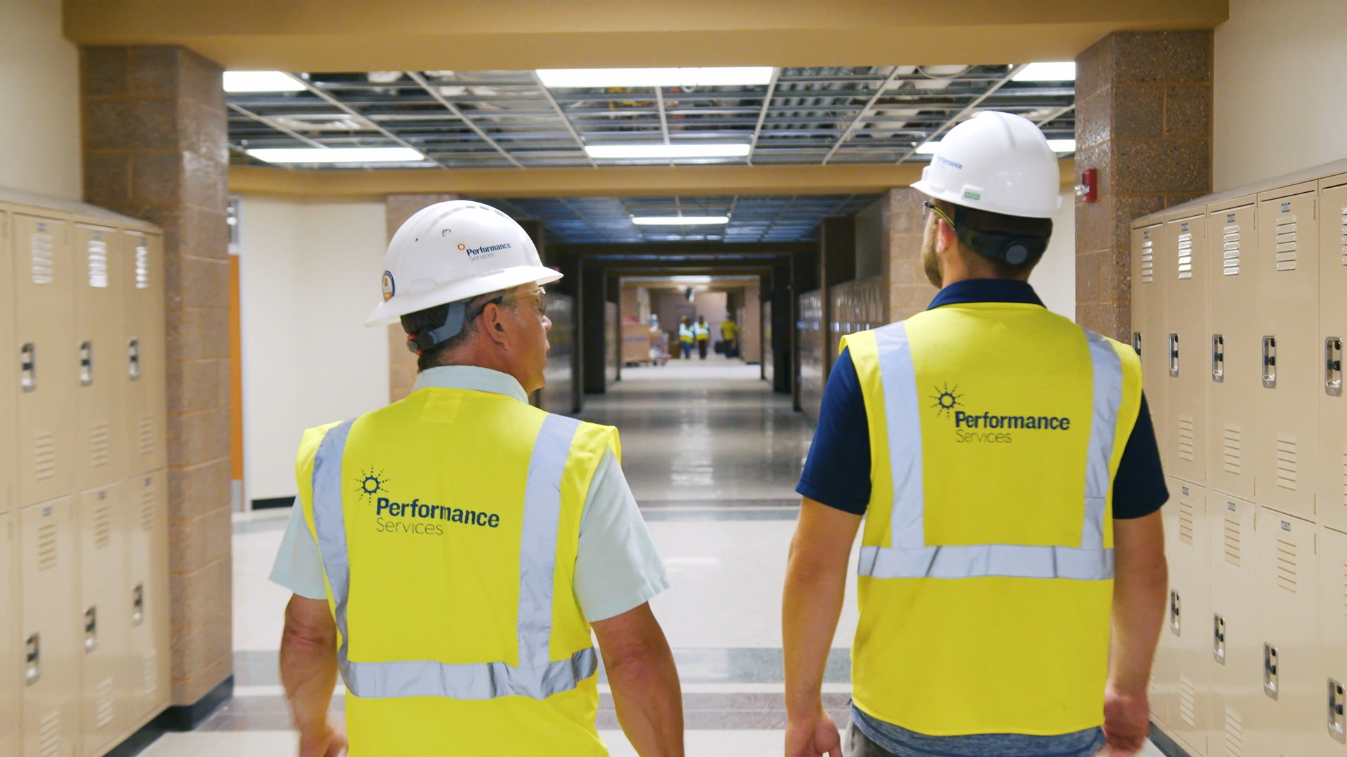 Two project managers walking an active construction in safety vests and hard hats