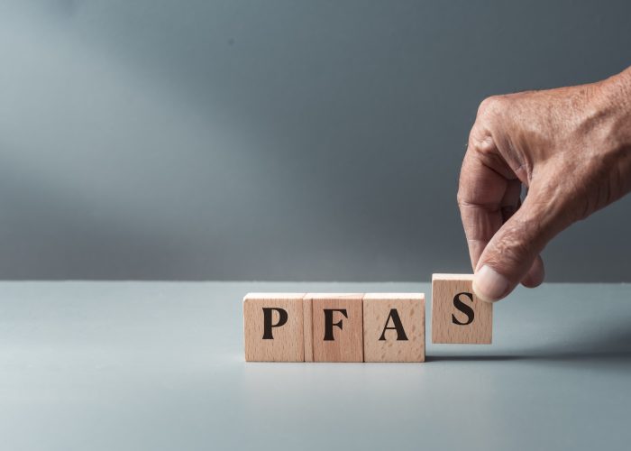 Hand holding blocked letters that spell out the forever chemical, PFAS, short for polyfluoroalkyl substances