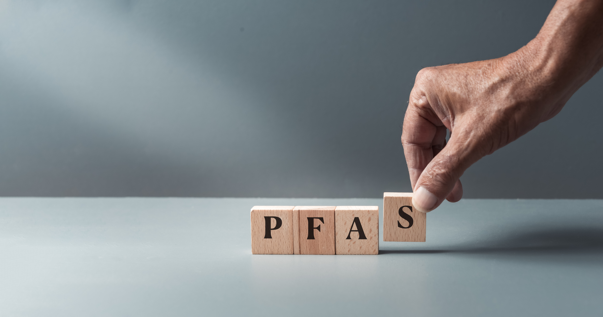 Hand holding blocked letters that spell out the forever chemical, PFAS, short for polyfluoroalkyl substances