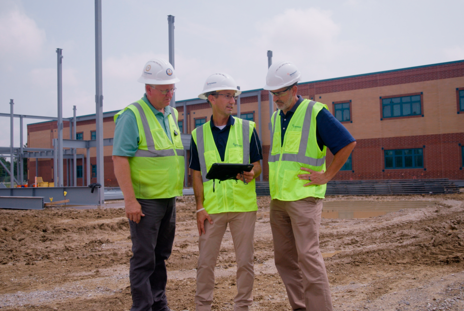 Performance Services design-build team collaborating on an active project site in hard hats and safety vests