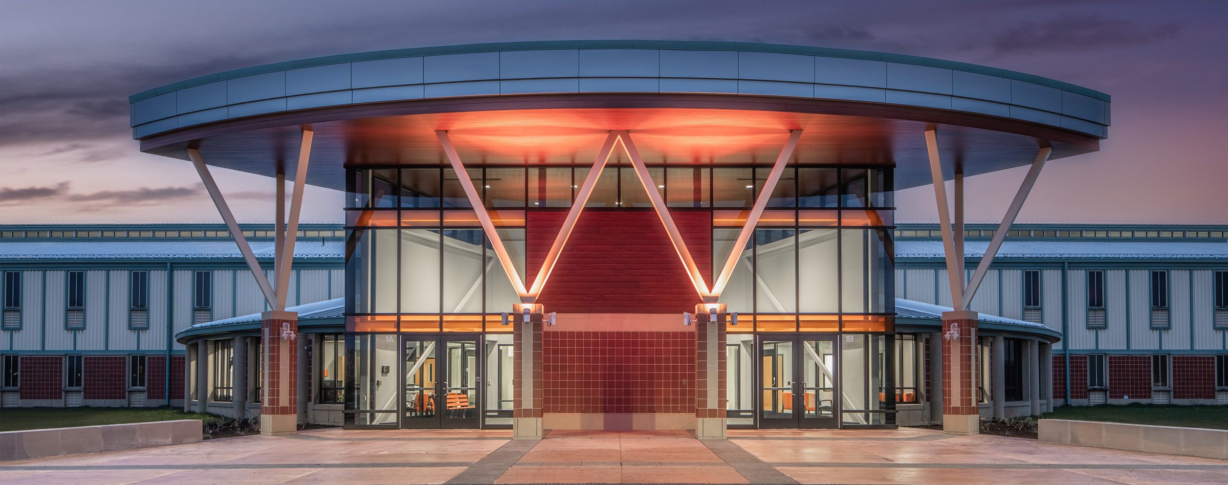 Warsaw Community High School exterior new entrance lit up at night with students walking in