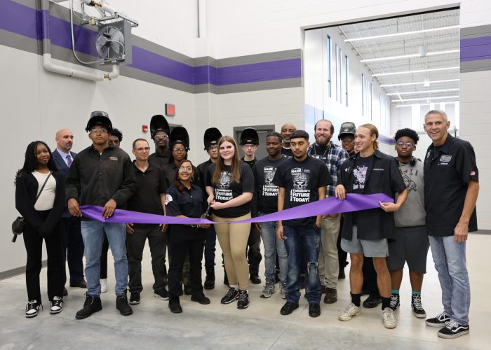 Students and staff from Merrillville Community Schools cutting a purple ribbon to celebrate the opening of the new career and technical education wing