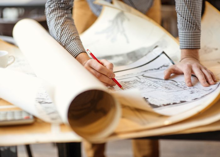 Close up of an architect's hands writing on architectural plans/drawings