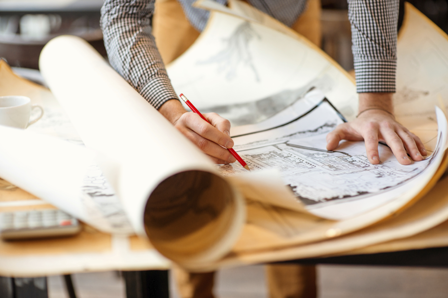 Close up of an architect's hands writing on architectural plans/drawings